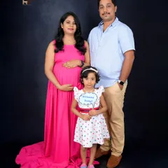 Welcoming a new member to the family. This maternity portrait includes the couple's older daughter, who holds a "Welcome Baby" sign, beautifully capturing the family's shared excitement.