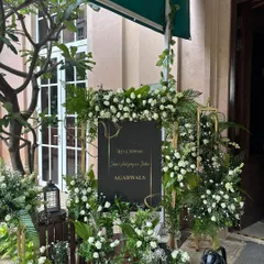 A closer look at the personalized welcome sign, showcasing the elegant typography and the beautiful frame of white flowers and ferns.