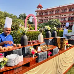A chef arranging desserts at an outdoor station. This setup, against the backdrop of a heritage property, showcases a colorful array of dessert cups and other sweet treats.