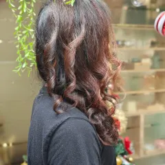 A side profile of a men's style, showcasing expertly crafted curls and a rich, subtle colour that adds dimension and character to long hair.