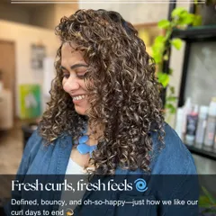 Fresh curls, fresh feels. This happy client is glowing after her curly cut and styling session, showing off defined, bouncy curls with beautiful highlights.