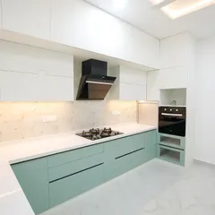A modern two-tone kitchen with mint green lower cabinets and white upper cabinets. The design includes an integrated oven and a sleek black chimney, creating a space that is both stylish and highly practical.