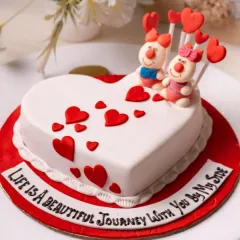A whimsical heart-shaped cake perfect for Valentine's Day or an anniversary. It features adorable fondant figures and the message, "Life is a beautiful journey with you by my side."