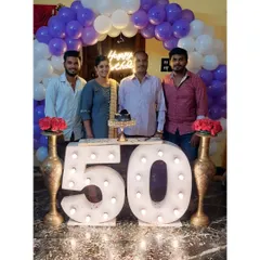 A family celebrating a 50th birthday with our marquee number setup. The large, lit-up "50" provides the perfect centerpiece, framed by a purple and white balloon arch for a festive and memorable family photo.