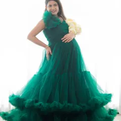 A stunning high-key portrait of a mom-to-be in a vibrant green ruffled gown. The bright lighting creates an angelic and ethereal feel.