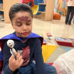 This little vampire is admiring his finished ghost lollipop. The face paint and costumes make our Halloween party extra special.