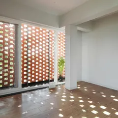 The effect of the brick jali screen from the inside. The perforations cast a beautiful, shifting pattern of light and shadow on the floor, creating a dynamic and poetic interior atmosphere.