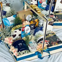 A luxury snack hamper featuring a wide array of gourmet treats, including TBH sweet potato chips, Waffle Mill crisps, and Smoor chocolates, presented in a beautiful wooden basket.