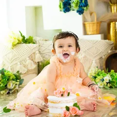 A picture of pure delight. Her face says it all as she enjoys her beautiful floral cake in a lovely boho-themed setup for her first birthday.