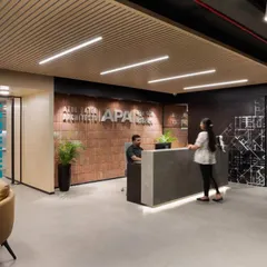 The reception area for a modern architecture firm, featuring a concrete desk, exposed brick, and warm wood tones. The design balances industrial aesthetics with a professional and creative feel.
