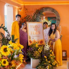The family poses by the "Halki si Haldi" sign. I styled them in a color palette of yellows and purples, which coordinated beautifully with the sunflower decor. It shows how outfits can tie into the overall event theme.