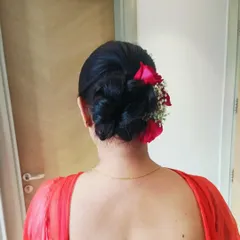 A voluminous low bun decorated with fresh red roses and baby's breath. This classic floral bun is a favorite for Indian wedding ceremonies.