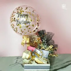 A classic birthday hamper that brings the celebration. It includes a festive 'Happy Birthday' balloon, a stylish checkered box filled with luxury essentials like Moët & Chandon, and a chic black and gold floral arrangement.