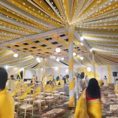 A yellow and white draped canopy lit with fairy lights for an evening Haldi or Sangeet event. The lighting adds warmth and a celebratory feel to the entire venue.