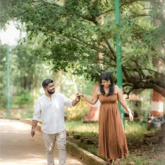 A playful and candid shot of a couple walking in a park, with the bride balancing on a ledge while holding her partner's hand. This captures their fun-loving dynamic.