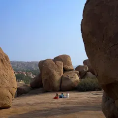 This shot gives a sense of the immense scale of the Hampi landscape. The people appear tiny against the ancient, sun-baked rocks.