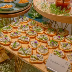 Our Truffle Mushroom Crostini, beautifully arranged on a wooden board. Each toast is generously topped with a creamy mushroom mixture and garnished with fresh chives and edible flowers.