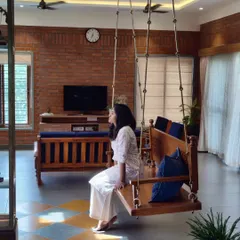 Another view of the living room in the Banashankari residence, where the wooden swing invites relaxation. The space is a dialogue between traditional craft and contemporary openness, bathed in natural light.