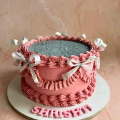 This personalized vintage cake for "Shrishti" features delicate pink piping, silver satin bows, and a glittering top, combining classic techniques with a touch of modern sparkle.