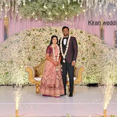 This reception stage features a massive cascade of white flowers, creating a luxurious and textured backdrop. The cold sparklers add a celebratory sparkle to the couple's portrait.