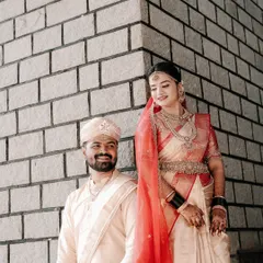 A stylish portrait of a South Indian couple in their wedding attire, posing against a modern brick wall, showcasing a blend of traditional and contemporary aesthetics.