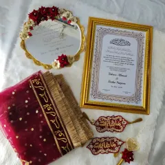 This is one of my complete Nikah sets, and it’s one of my babies. It includes a personalized framed Nikah Nama, a 'Muah Dekhaye' mirror, a 'Qubool Hai' dupatta, and beautifully detailed 'Masha-Allah' hangings. Everything is coordinated in rich maroon and gold to bring a royal touch to your ceremony.
