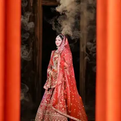 A stunning bridal portrait with a cinematic feel. The bride is framed by orange pillars, with smoke creating a dreamy, ethereal atmosphere around her.
