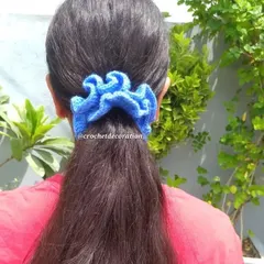 Our handmade crochet scrunchie, shown here holding a ponytail. It's made from soft, stretchable yarn that is gentle on your hair.