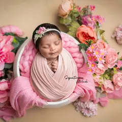 Wrapped in love and surrounded by pink peonies. This classic potato sack pose is a favorite for showcasing how tiny and curled up newborns are, creating a beautiful, artistic portrait.