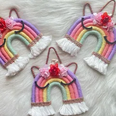 A trio of magical unicorn wall hangings. Each features a pastel rainbow with delicate flower embellishments, perfect for adding a touch of fantasy to a child's room.