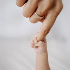 The simple, profound connection of a newborn's hand gripping their parent's finger. This macro shot captures the strength in that tiny grasp.