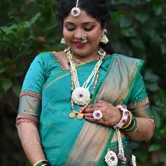 A serene portrait of the mom-to-be. The teal green saree and matching floral jewelry create a harmonious and traditional look for her baby shower.