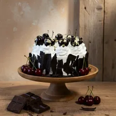 This is my modern take on the classic Black Forest cake. I use layers of rich, eggless chocolate sponge, fresh whipped cream, and a tart cherry compote, all decorated with architectural dark chocolate shards and gold-leaf cherries for an elegant finish.