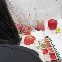 A student practices painting a red bell pepper from life, focusing on capturing its form, color, and texture. This kind of object study is essential preparation for the still life section of the drawing exams.