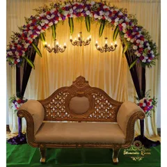 For a traditional baby shower, we created this stunning floral arch with rich purple and red flowers over an ornate carved sofa. The setup includes classic chandeliers and a fabric drape backdrop for a truly regal feel.