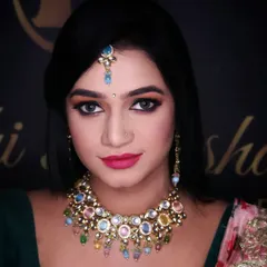 A close-up of a glamorous party look. The sharp winged eyeliner and bold pink lip are the stars here, perfectly complementing the colorful stone-studded necklace for a vibrant and modern style.