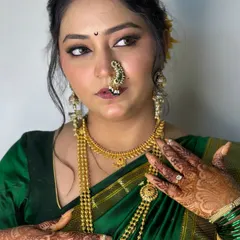 A close-up showcasing the details of a 'Vidhi' look. Notice the subtle smokey eye, the perfectly placed nath, and the glow that radiates from within, set against a traditional green saree.