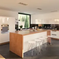 A bright, contemporary kitchen with a large wooden island that provides seating for four. The high-gloss white cabinets and large window create an open and airy feel, perfect for family gatherings.
