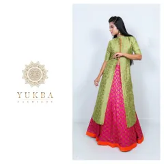 A modern interpretation of traditional wear. This outfit features a pink brocade skirt paired with a long green jacket-style top, creating a chic and layered look for any celebration.