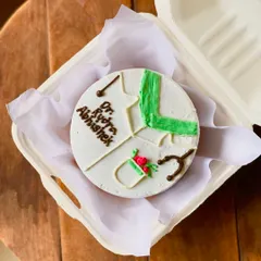 A thoughtful cake for a doctor, Dr. Kyra Abhishek. The design includes a doctor's coat, a stethoscope, and a small bouquet of flowers, making it a perfect professional milestone cake.