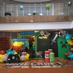 We built a complete Minecraft world for this 8th birthday bash. The setup included a pixelated green wall, character cutouts, and balloon arrangements shaped like game elements like TNT and controllers.