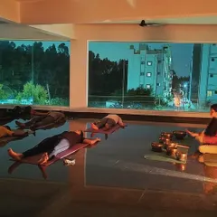 A nighttime sound meditation session where participants are immersed in deep relaxation. The large windows connect the serene indoor space with the quiet of the evening outside, creating a perfect environment for healing.