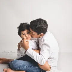 A tender moment between two brothers in the studio. The older brother wraps his arms around his younger sibling, showcasing a protective and loving bond.