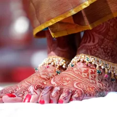 A close-up of the bride's feet, adorned with beautiful anklets and intricate Mehndi. We believe in capturing every detail of the bridal attire.