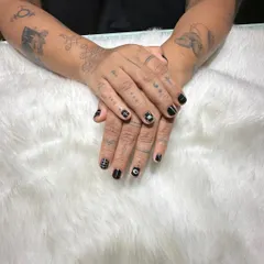 This view shows how the graphic black and white nail art complements the client's hand tattoos, creating a cohesive and artistic personal style.