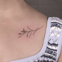 A delicate floral sprig placed perfectly on the collarbone. This is a great example of a minimalist tattoo that is both subtle and beautiful, using clean lines to create an elegant piece.
