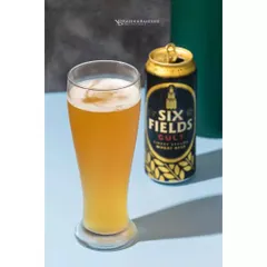 A straightforward and refreshing shot of Six Fields Cult wheat beer. The focus is on the crisp, cold look of the beer in a tall glass, with the can placed clearly beside it. This clean style is effective for catalog and website imagery.