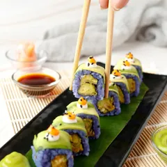 A colourful and creative sushi roll with purple rice being picked up by chopsticks.