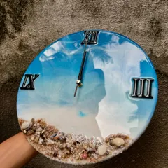 A slightly different angle of the ocean wall clock, showing how the light reflects off the glossy surface. The details of the shells and sand at the bottom bring a piece of the beach into your home.