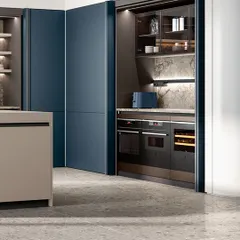 A prime example of concealed design. These floor-to-ceiling blue panel doors slide away to reveal a fully equipped appliance station, keeping the kitchen's aesthetic minimal and sleek when not in use.